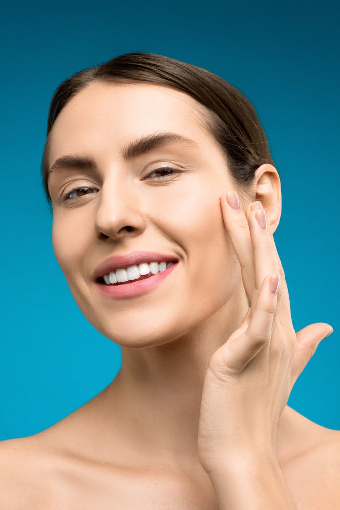 photo by shiny diamond Close-up of a young woman with smooth skin smiling brightly against a blue background.
